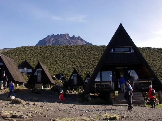 Climbers at Uhuru Peak summit sign on Kilimanjaro at sunrise